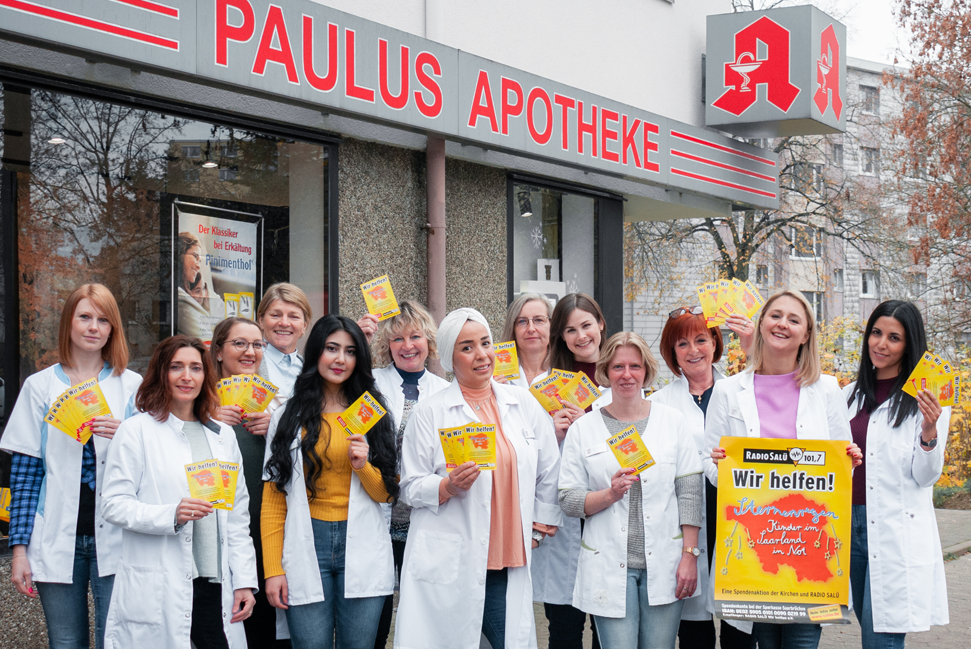 Das Team der Paulus Apotheke Saarbrücken vor der Apotheke mit Zetteln für die Aktion Radio Salue Sternenregen in der Hand